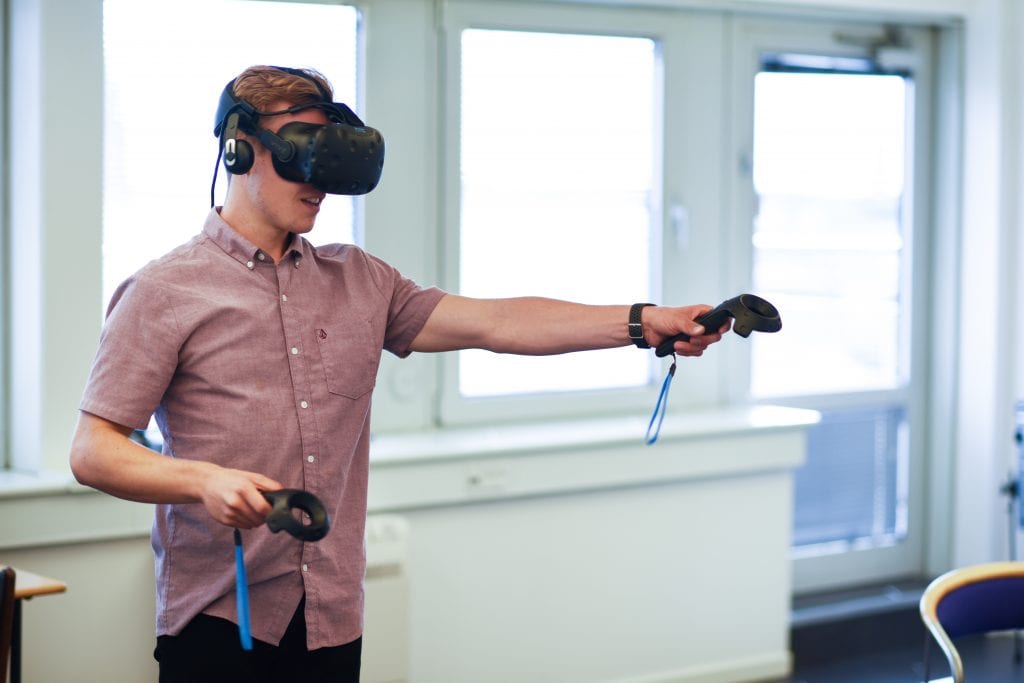 Man wearing VR headset with joystick in extended arm