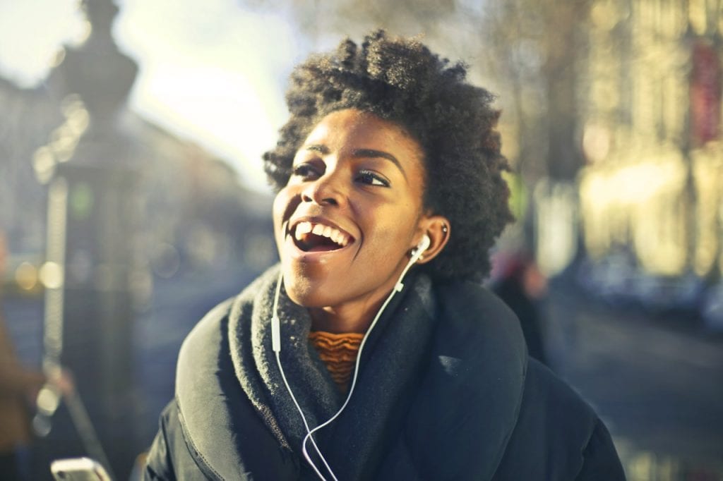 happy girl wearing earphones and scarf in a city landscape