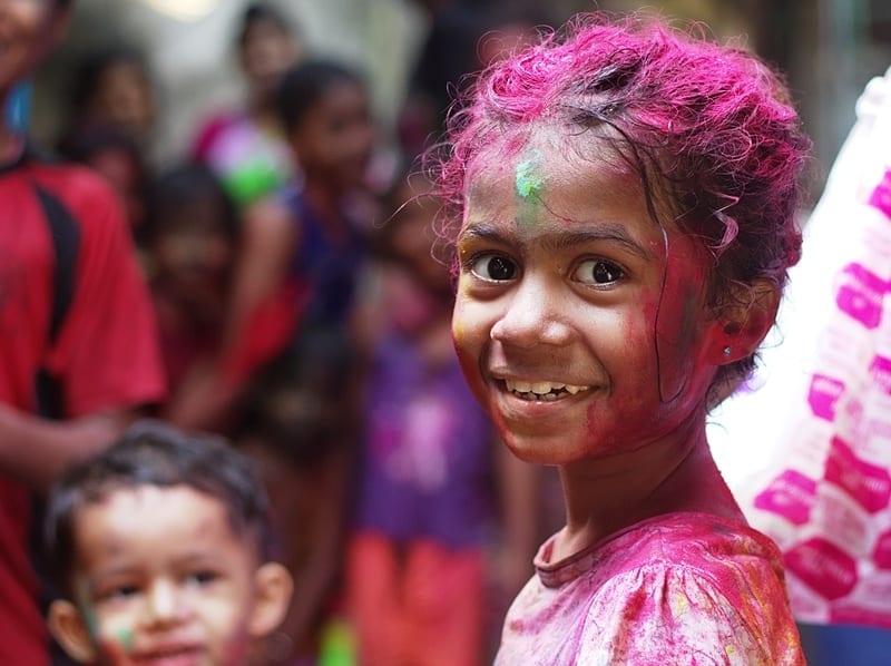 closeup of a smiling little girl with paint on her hair, face, and clothes