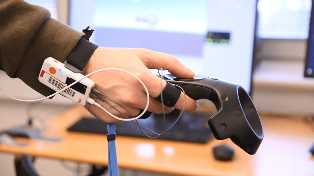 hand with biometric sensors holding a virtual reality remote controller